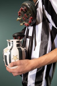 a man wearing a black and white striped shirt holding a vase