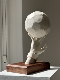 a sculpture of a hand holding a soccer ball