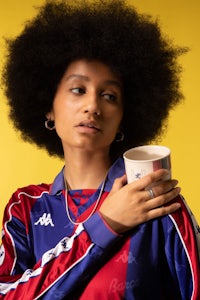 a woman with an afro holding a cup of coffee